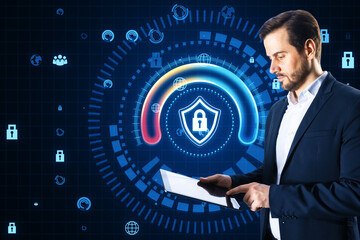 Wall Mural - Attractive young businessman using tablet with glowing round padlock shield hologram on blurry blue background. Digital safety, protections and web concept.