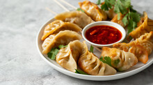 Steamed Momos With Red Chili Chutney On A White Plate Over A Grey Background, Asian Cuisine