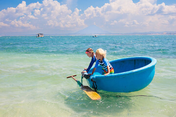 Family vacation to Vietnam. Kids in round boat.