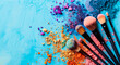 Makeup brushes with vibrant powder explosion on blue textured background, beauty concept.