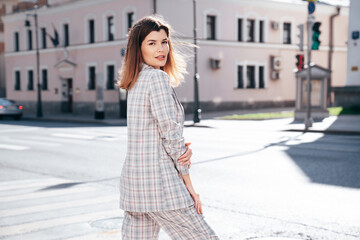 Poster - Portrait of young beautiful brunette woman wearing nice trendy plaid suit jacket. Sexy smiling model posing in the street at sunny day. Fashionable female outdoors. Cheerful and happy.