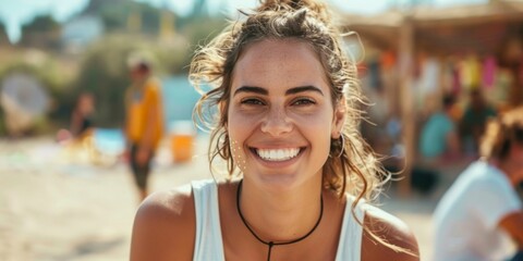 Joyful young woman with a carefree smile enjoying a sunny beach party with friends in the background.