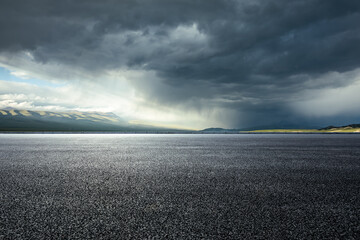 Wall Mural - Asphalt road and mountains with dark clouds before heavy rain