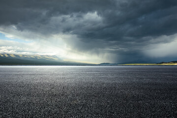 Canvas Print - Asphalt road and mountains with dark clouds before heavy rain