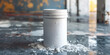 A white paint can lies among dry spilled powder on a reflective surface in a dimly lit area