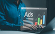 © Supatman - Ad on website and social media, banner ads on internet, Digital marketing concept. Marketer analyzing online advertising campaigns and performance metrics on a laptop with a graphical data interface.