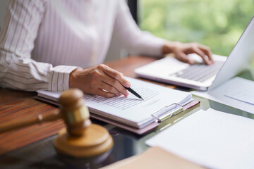 Lawyer woman reading and checking legal agreement of business contract to typing data on laptop