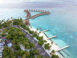 Fototapeta Mosty linowy / wiszący - Aerial view from the drone of bungalows on the water, tourist village in maldives.