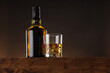 Whiskey with ice cubes in glass and bottle on wooden table, low angle view. Space for text