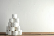 Stack Of Toilet Paper Rolls On Wooden Table And White Wall Background.