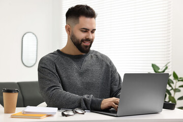 Sticker - E-learning. Young man using laptop during online lesson at white table indoors