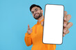 © New Africa - Happy man holding smartphone with empty screen on light blue background, space for text