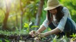 © Sara_P - Woman gardening nurturing a plant on a lush green background a connection to nature with generous copyspace
