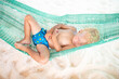 © famveldman - Baby sleeping on tropical beach. Child in hammock.