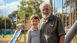 © Nemanja - Grandpa and his grandson standing in the park outdoors, old senior man and a little toddler boy on the playground with slides, hugging each other, looking at the camera and smiling, relationship