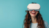 Fototapeta  - Close-up of young laughing enthusiastic woman wearing white augmented virtual reality glasses on studio blue background with copy space