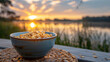 A hearty oatmeal bowl, with a calm lake reflection as the background, during a serene dawn