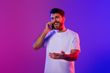 Poster - Cheerful young man happily chatting on his mobile phone, studio