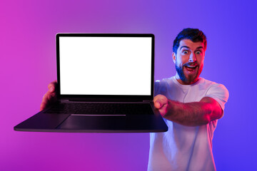 Poster - Emotional guy showcasing blank laptop screen advertising websites, neon backdrop