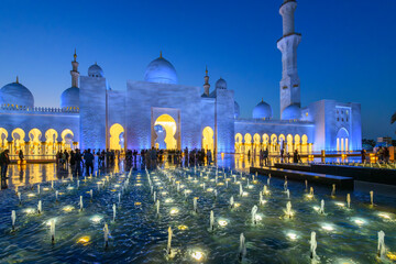 Wall Mural -  Hundreds of illuminated water fountain lights at blue hour twilight at the entrance to Sheikh Zayed Grand Mosque in Abu Dhabi, United Arab Emirates.
