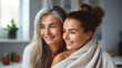 Two multiracial women wrapped in white towels are smiling at the camera