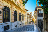 Fototapeta Uliczki - The narrow, ornately decorated Calle Oficios street alongside the Capilla Real de Granada, or Royal Chapel and Cathedral of Granada in the Andalusian city of Granada, Spain.