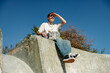 © Kostiantyn - Low angle of young male skateboarder holding skateboard sitting on ramp in skate park
