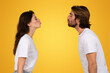 Side profile of a young man and woman in white t-shirts facing each other with puckered lips
