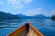 POV riding a canoe on a lake surrounded by mountains on a summer day