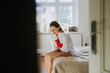© Halfpoint - Woman at home suffering from menstrual pain, having cramps. Woman warming lower abdomen with a hot water bottle, endometriosis, and conditions causing pain in tummy.