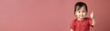 © Rodrigo - Affirmative Charm: Endearing Asian Toddler in Red Giving a Confident Thumbs Up on a Rose Background