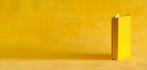 Wall Mural - Single yellow book in front of a yellow background, reading,education,learning concept,negative space technique, large copy space