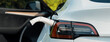 Closeup EV electric car recharge battery at parking lot in green city park. Alternative clean energy technology for rechargeable automobile for sustainable eco friendly urban travel.Panorama Expedient