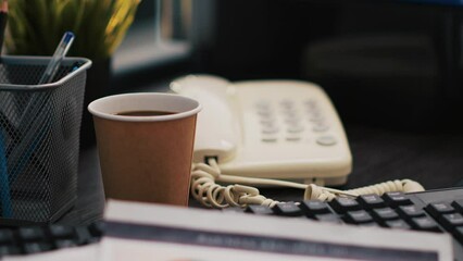 Poster - Cup of coffee and paperwork on office desk containing company profit analysis, close up shot. Business documents, hot beverage and telephone on table in accounting workplace