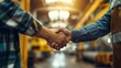 © tashechka - Two people engage in a firm handshake in a warehouse or industrial environment.
