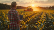 © tong2530 - Asian young farmer with laptop standing in corn field, tractor and combine harvester working in corn field in background.