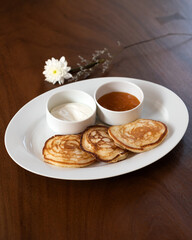 Pancakes served with caramel sauce and sour cream, garnished with a flower.