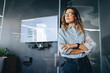 © Jacob Lund - Pensive business woman standing in a modern workplace with crossed arms