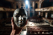 A Person In An Old, Empty Theater, Holding A Faded Stage Mask, With Intricate Stage Lighting Casting Dramatic Shadows