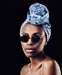 Wall Mural - Portrait, fashion and sunglasses with African woman in studio isolated on black background for heritage. Aesthetic, face and tradition with confident young person in trendy headwear for style culture