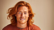 Handsome young male guy smile Asian with long red hair, on creamy beige background, banner, copy space, portrait.