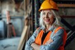 © MediaRaw - A woman wearing a yellow hard hat and orange vest stands in front of a wall
