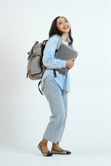 full leght shoot of happy asian Indonesian woman wearing casual attire, holding laptop and backpack on isolated background