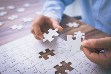 Wall Mural - Closeup hand of woman connecting jigsaw puzzle. Business solutions, success and strategy concept.