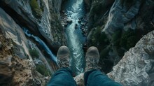 The Traveler's Feet Stand On The Edge Of A Cliff On A Rock. Person Looks Down An Abyss With A Mountain River