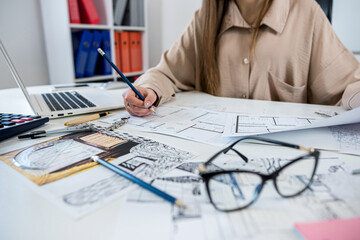 Wall Mural - Young woman designer working with house sketch plan blue print in the office