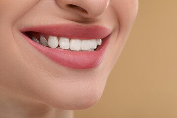 Wall Mural - Young woman with beautiful smile on beige background, closeup