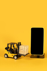 Wall Mural - A yellow forklift is lifting a box and a phone is next to it