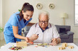 © Studio Romantic - Nurse in geriatric clinic or retirement home helping patient with alphabet puzzle. Senior man sitting at desk and playing games with letters. Old age, dementia, Alzheimer's disease, therapy concept