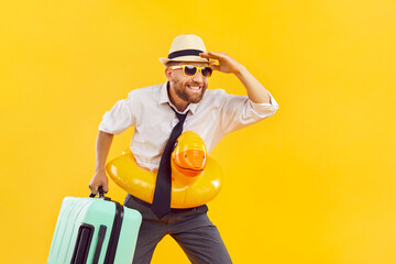 Happy man in office wear, sun hat, luggage with rubber inflatable duck ring summer holiday dream. Leisure and recreation, travelling to enjoy happy activity, weekend fun, bright yellow background 